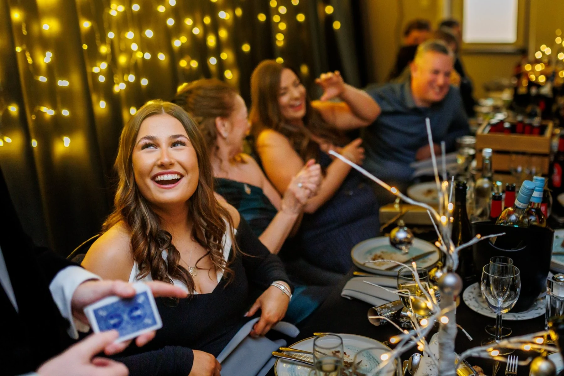 Guests smiling as Ben performs card magic at a Christmas party
