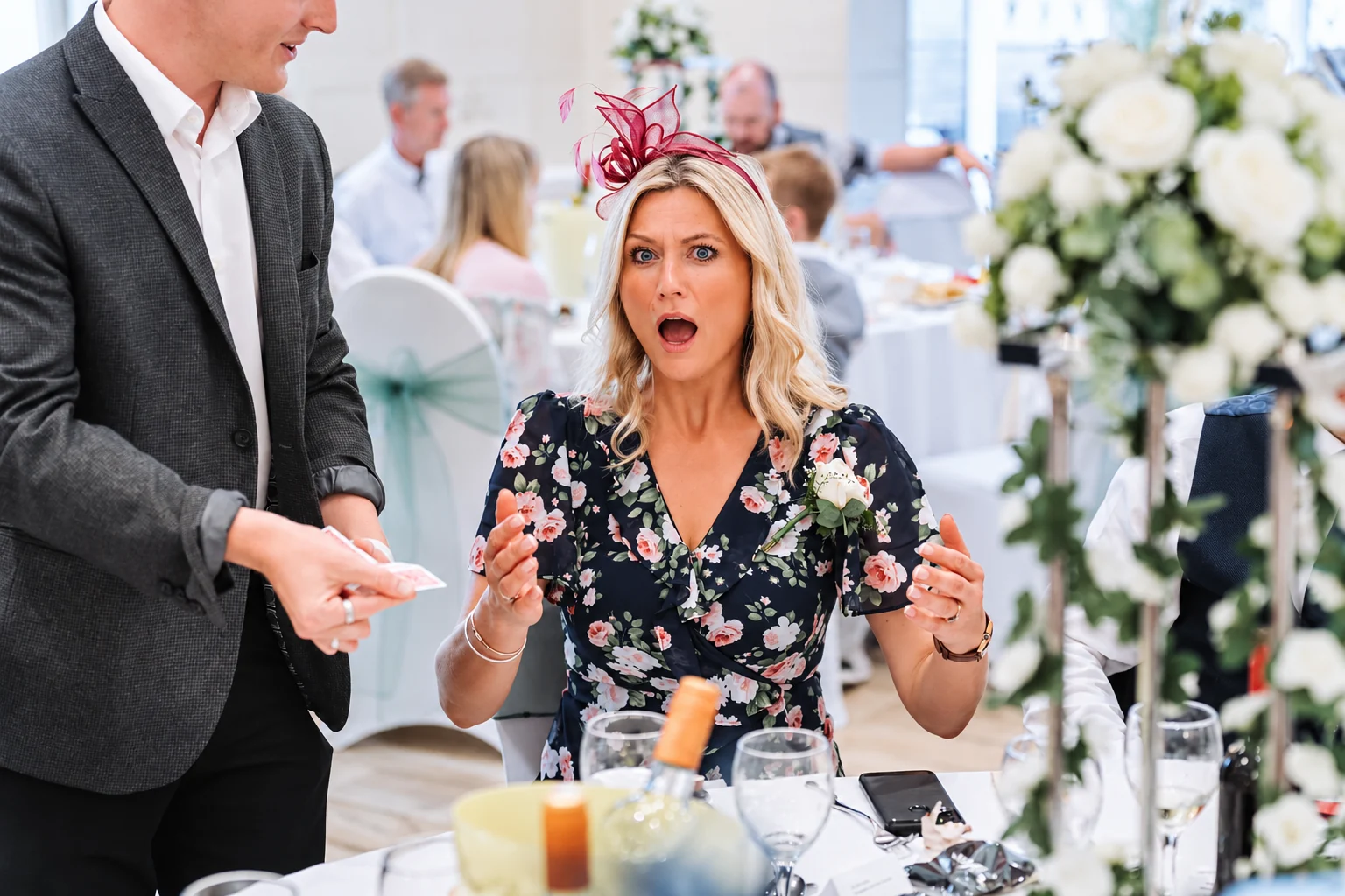 A seated wedding guest reacting with surprise to Ben’s close-up magic